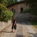 A woman walks along a stone path by a historic building in Lonato del Garda, Italy.