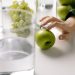 Refreshing image of green apples and grapes with glasses of water on a table, promoting healthy living.